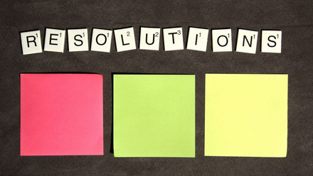 'Resolutions' written in scrabble letters. Below are three different colour post-it notes.