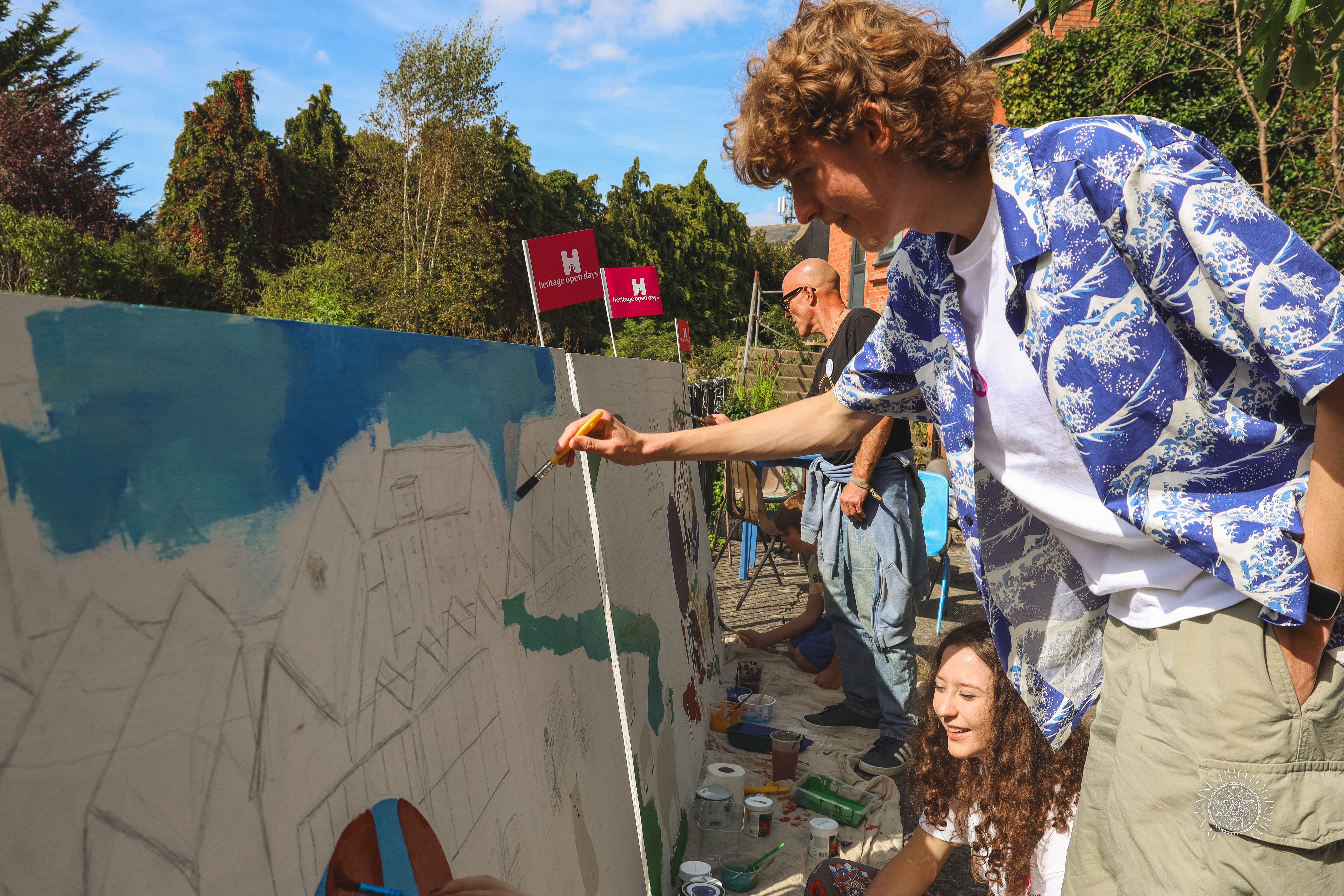 Four people painting on a large blank mural