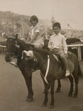 Old photograph of two children on horses at the seaside.