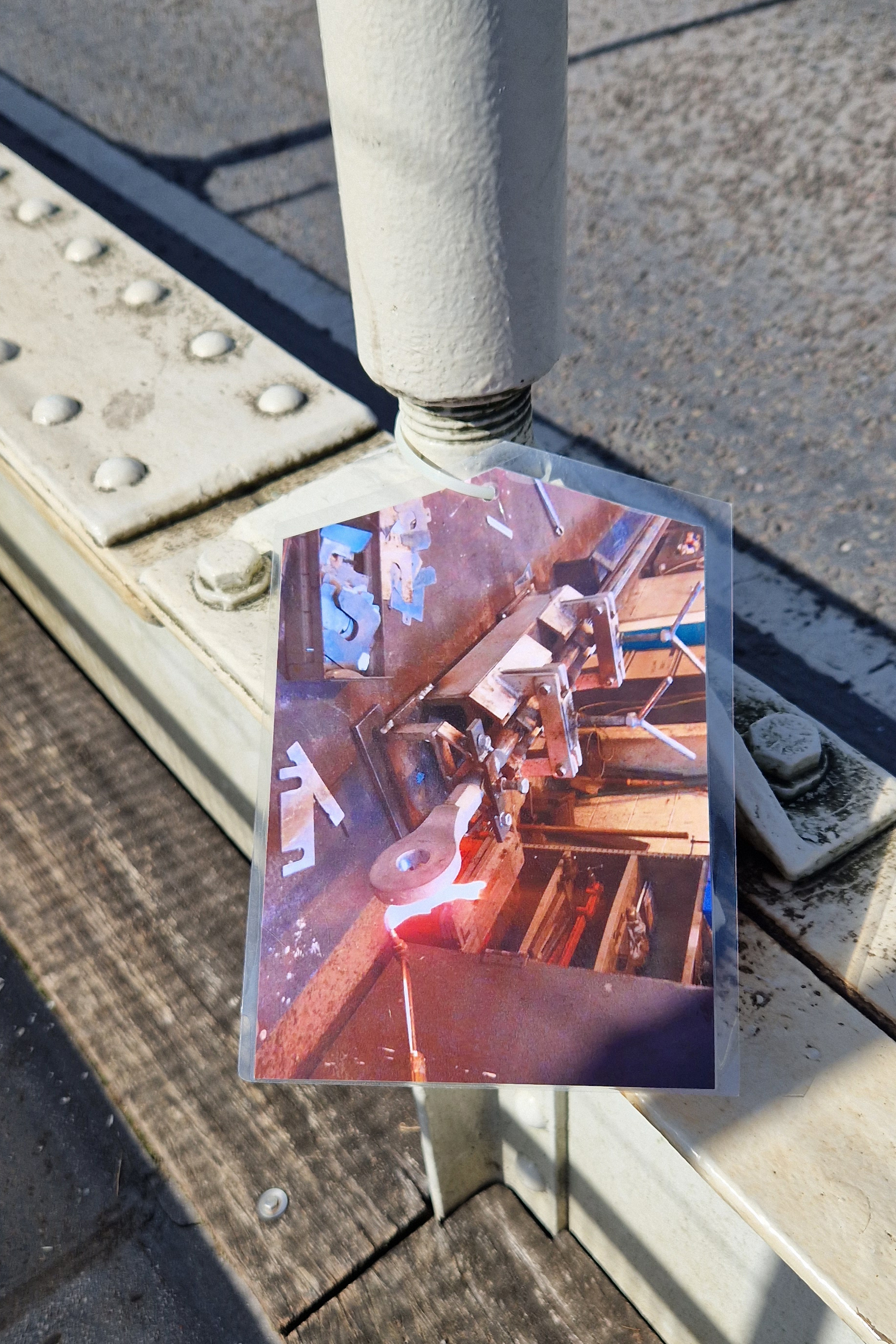 Big label printed with a photograph of metal components, attached to a metal strut.