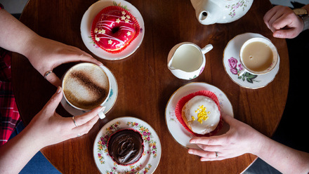 Birds eye view of two people having tea and sticky buns at a round wooden table.