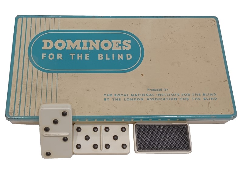 Old box of dominoes with some propped up in front of it.